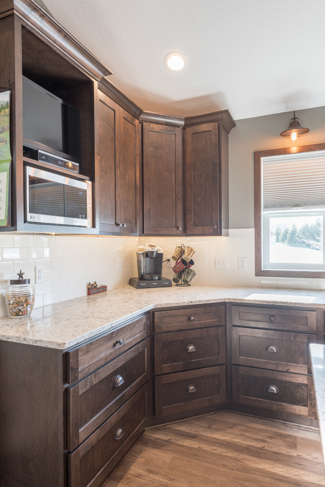 Example of a large mountain style u-shaped dark wood floor and brown floor enclosed kitchen design in Minneapolis with a double-bowl sink, shaker cabinets, dark wood cabinets, granite countertops, white backsplash, subway tile backsplash, stainless steel appliances and an island