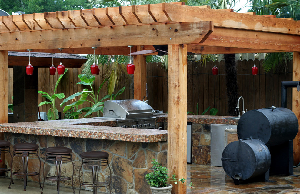 Inspiration for a mid-sized traditional backyard patio in Houston with an outdoor kitchen, natural stone pavers and a pergola.