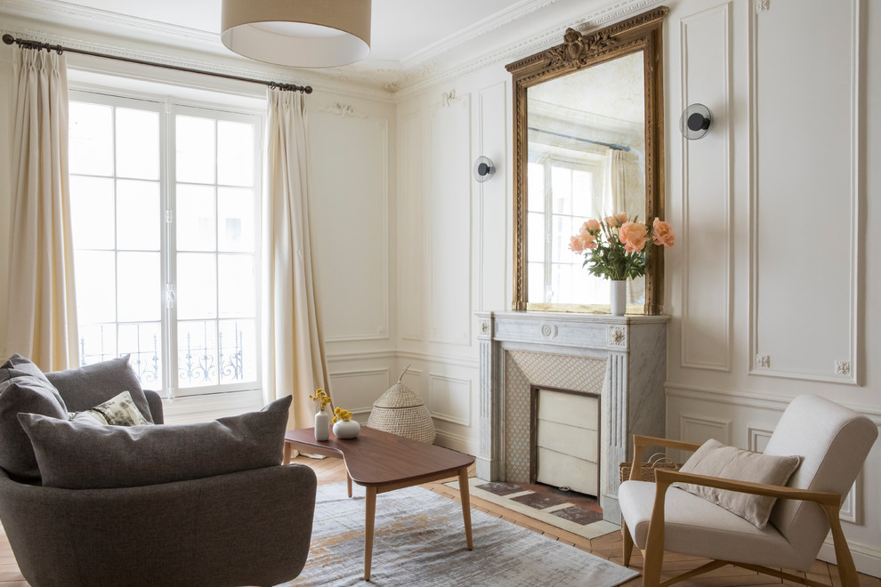 Inspiration for a mid-sized transitional living room in Paris with white walls, a standard fireplace, brown floor, light hardwood floors, a stone fireplace surround and no tv.