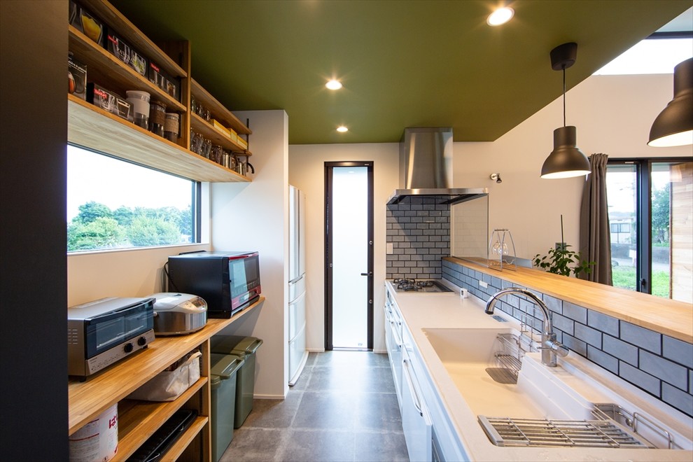 Photo of a mid-sized midcentury single-wall open plan kitchen in Other with open cabinets, medium wood cabinets, solid surface benchtops, grey splashback, ceramic splashback, black appliances, with island, white benchtop, an integrated sink and grey floor.