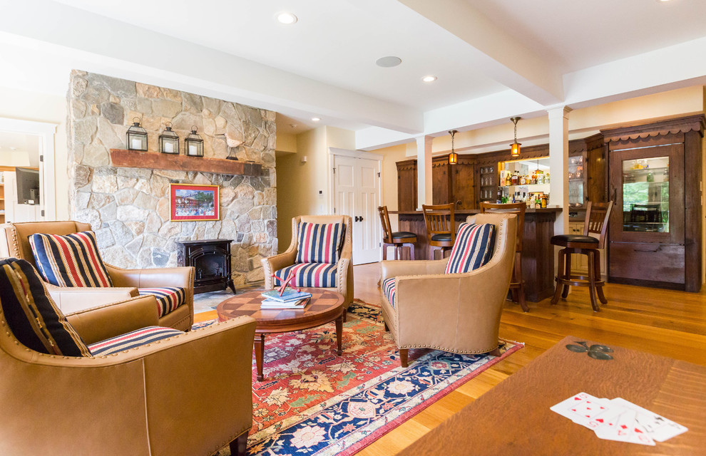 This is an example of an expansive arts and crafts walk-out basement in New York with white walls, medium hardwood floors, a wood stove and a stone fireplace surround.