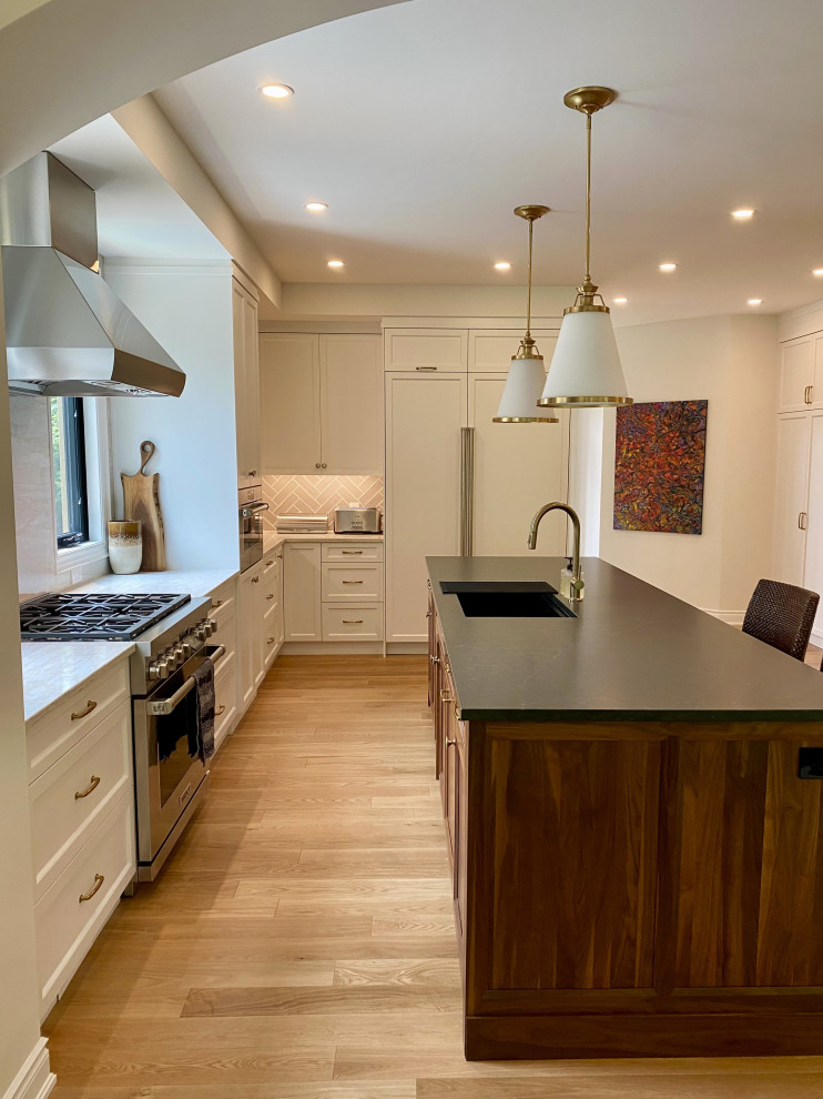 Example of a large transitional l-shaped light wood floor open concept kitchen design in Toronto with an undermount sink, recessed-panel cabinets, white cabinets, quartz countertops, paneled appliances and an island