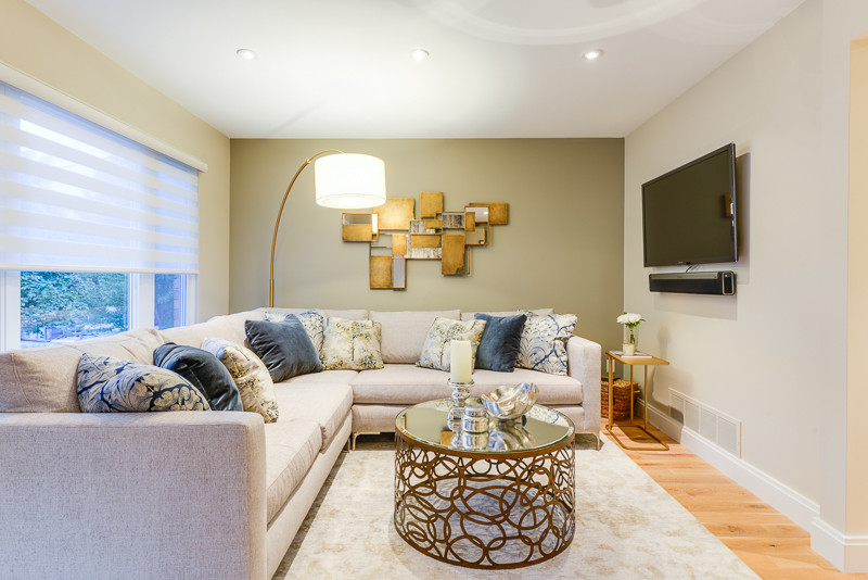 Photo of a mid-sized transitional open concept living room in Toronto with beige walls, light hardwood floors and a wall-mounted tv.