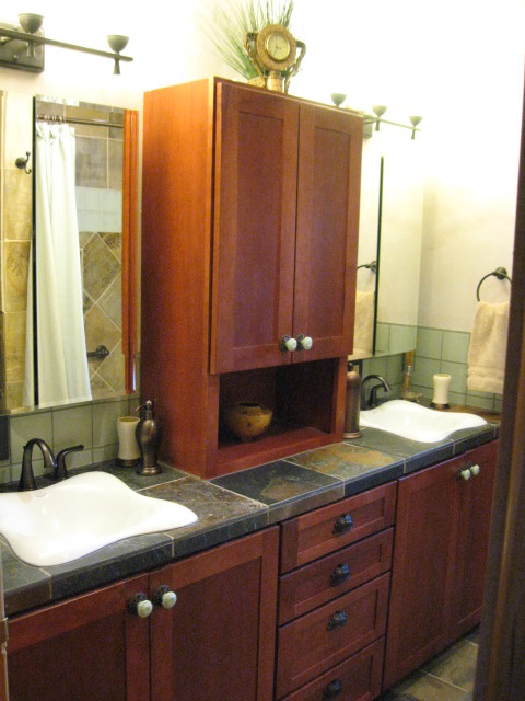 Design ideas for a small traditional bathroom in Seattle with a drop-in sink, recessed-panel cabinets, dark wood cabinets, tile benchtops, an alcove tub, a shower/bathtub combo, a two-piece toilet, stone tile, beige walls and slate floors.