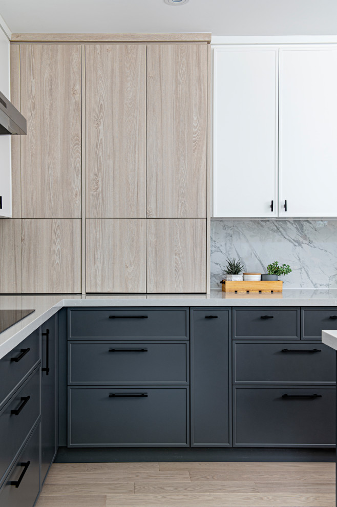 Large scandinavian l-shaped kitchen/diner in Toronto with a submerged sink, shaker cabinets, light wood cabinets, engineered stone countertops, grey splashback, porcelain splashback, stainless steel appliances, light hardwood flooring, an island and white worktops.