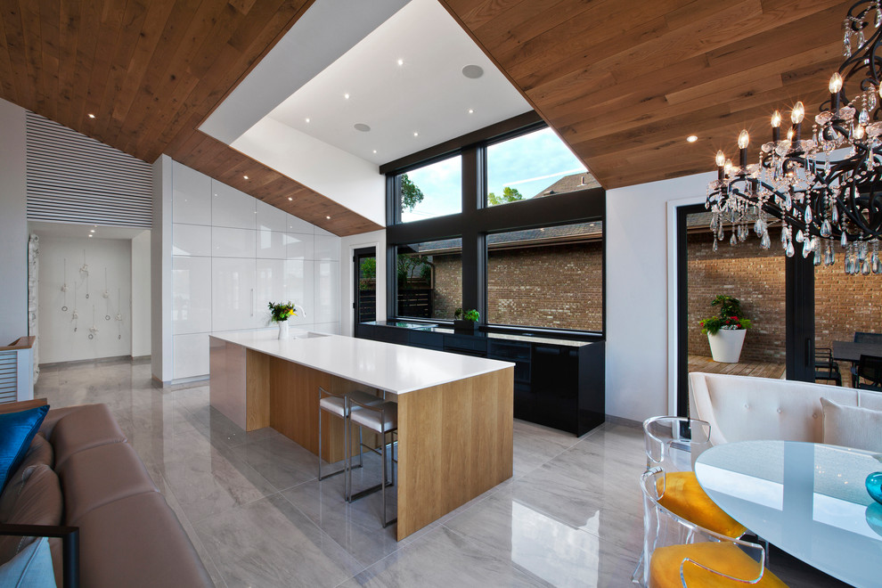 Mid-sized modern galley open plan kitchen in Indianapolis with an undermount sink, flat-panel cabinets, white cabinets, quartz benchtops, black splashback, timber splashback, black appliances, porcelain floors, with island, grey floor and white benchtop.