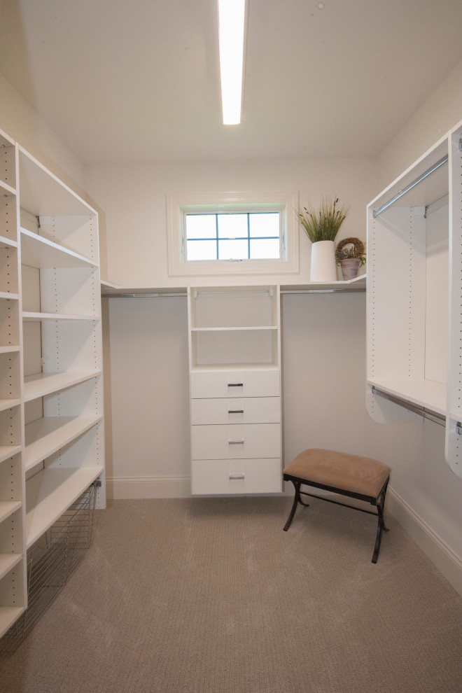 This is an example of a large transitional gender-neutral walk-in wardrobe in Milwaukee with open cabinets, white cabinets, carpet and beige floor.