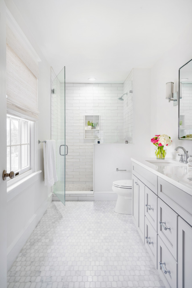 Mid-sized transitional master bathroom in Philadelphia with grey cabinets, porcelain tile, white walls, marble floors, a hinged shower door, recessed-panel cabinets, an alcove shower, white tile, an undermount sink, white floor and white benchtops.