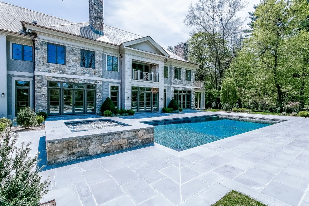 Photo of a large traditional backyard rectangular lap pool in New York with a hot tub and natural stone pavers.