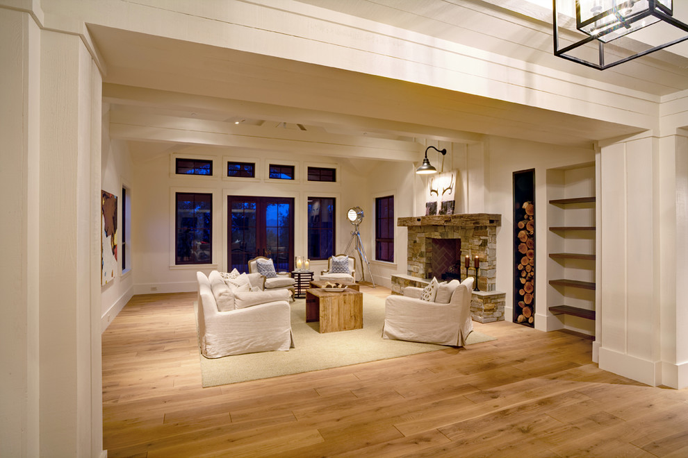 This is an example of a mid-sized country open concept living room in San Francisco with beige walls, light hardwood floors, a standard fireplace and a stone fireplace surround.