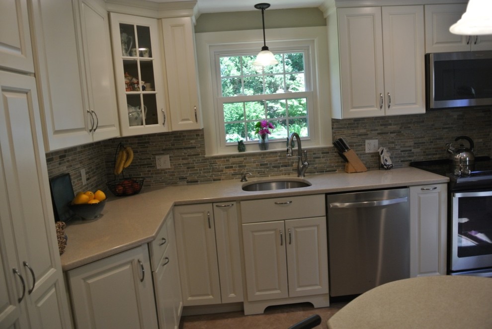 Inspiration for a transitional u-shaped porcelain tile and beige floor kitchen remodel in Boston with an undermount sink, raised-panel cabinets, white cabinets, beige backsplash, subway tile backsplash and stainless steel appliances