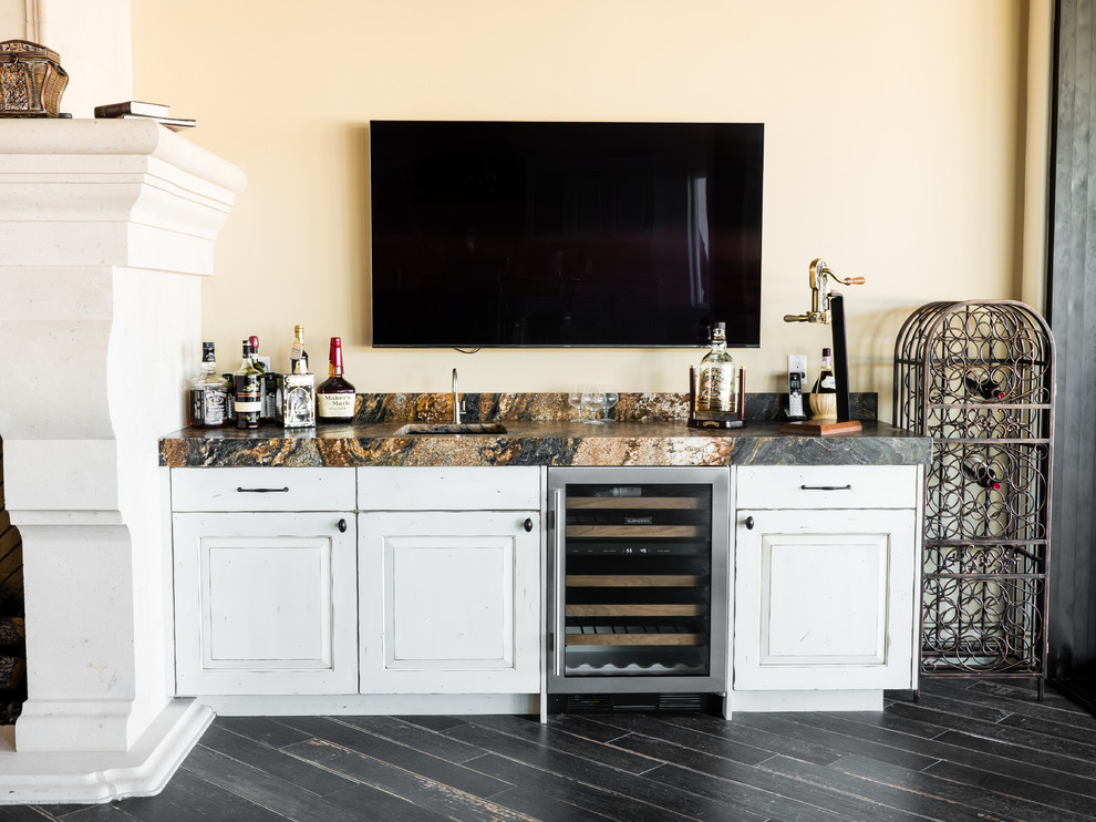Design ideas for a small traditional single-wall wet bar in Phoenix with raised-panel cabinets, distressed cabinets, granite benchtops, porcelain floors and black floor.