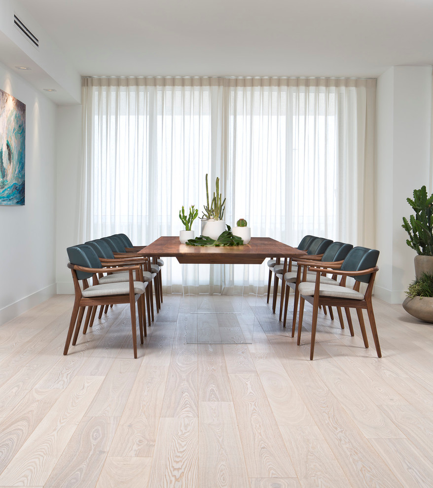 Photo of a beach style dining room in Miami with white walls and light hardwood floors.