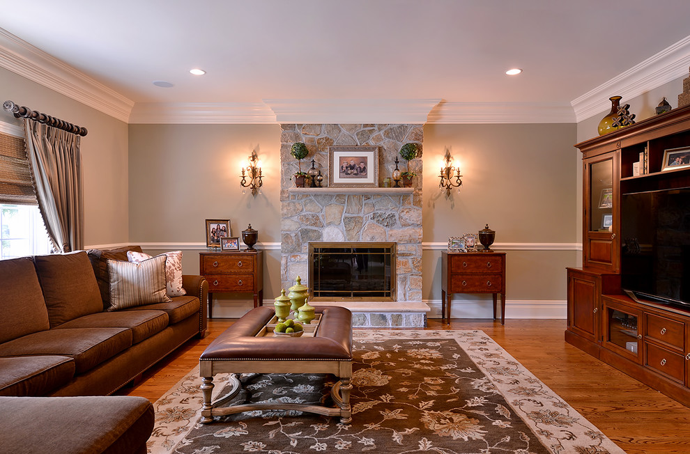 This is an example of a large traditional enclosed family room in New York with green walls, dark hardwood floors, a standard fireplace, a stone fireplace surround and a built-in media wall.