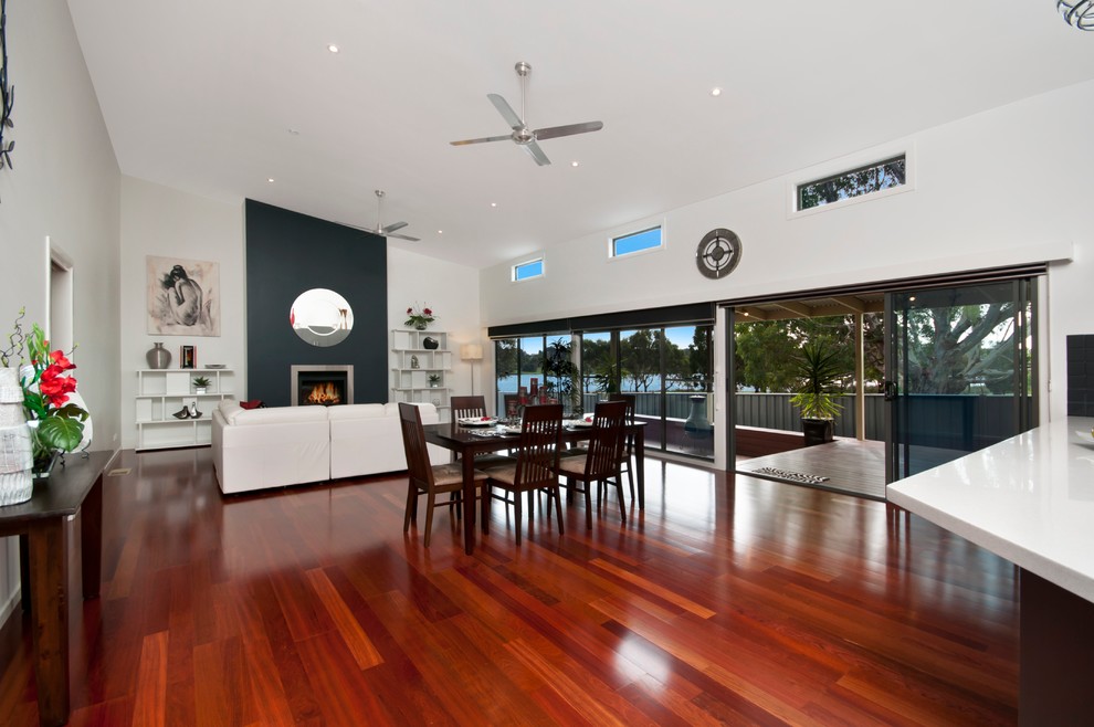 This is an example of an expansive contemporary open plan dining in Melbourne with white walls and medium hardwood floors.