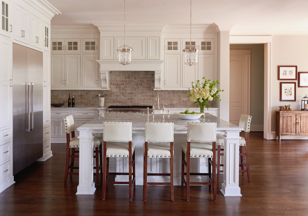 Inspiration for a traditional kitchen in Charlotte with recessed-panel cabinets, white cabinets, beige splashback, subway tile splashback, stainless steel appliances, medium hardwood floors and with island.