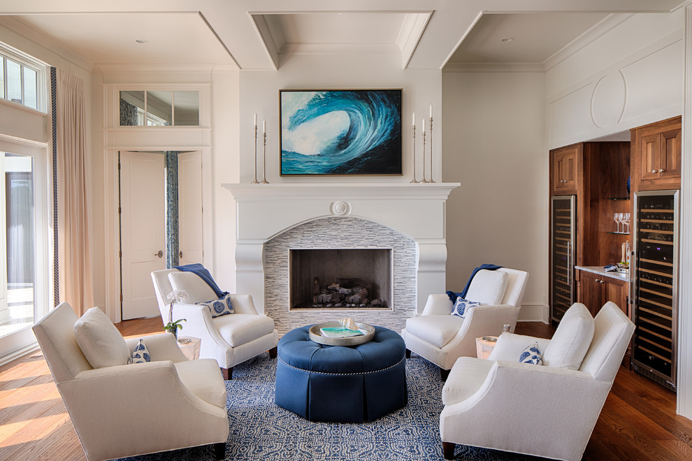This is an example of a beach style living room in Atlanta with a home bar, white walls, medium hardwood floors, a standard fireplace and a tile fireplace surround.