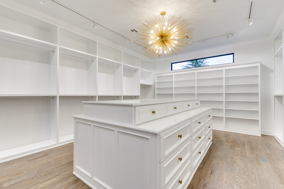 This is an example of an expansive modern gender-neutral walk-in wardrobe in Oklahoma City with shaker cabinets, white cabinets and medium hardwood floors.