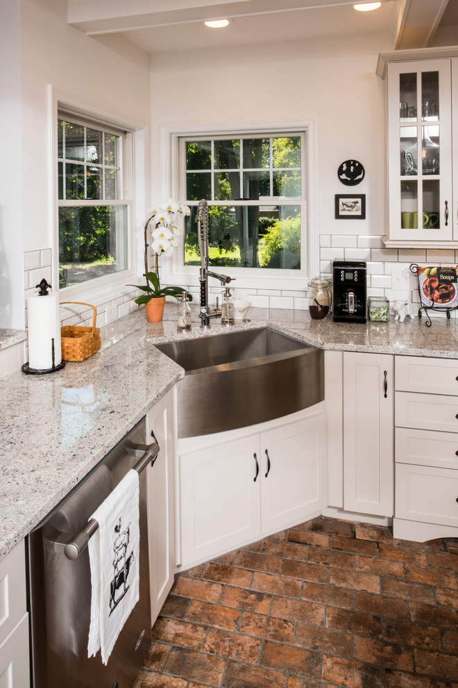 Photo of a large country l-shaped eat-in kitchen in New York with a farmhouse sink, shaker cabinets, white cabinets, granite benchtops, white splashback, subway tile splashback, stainless steel appliances, terra-cotta floors and with island.