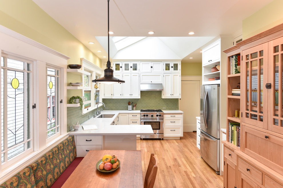 Mid-sized arts and crafts u-shaped eat-in kitchen in San Francisco with a single-bowl sink, shaker cabinets, white cabinets, quartz benchtops, green splashback, ceramic splashback, stainless steel appliances, medium hardwood floors and a peninsula.