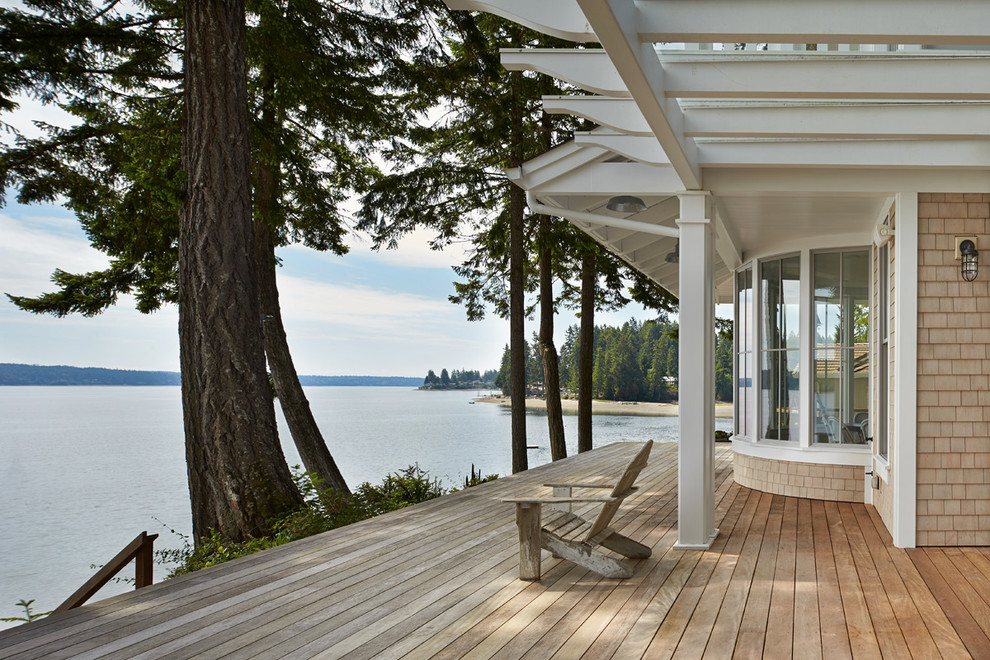 This is an example of a beach style deck in Seattle with a roof extension.