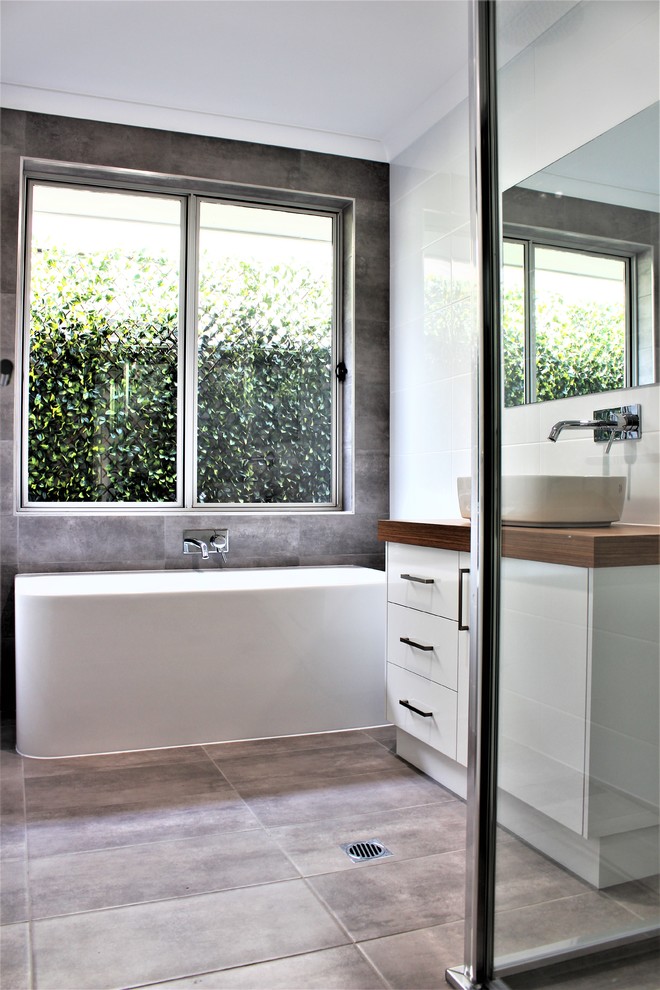 This is an example of a mid-sized modern kids bathroom in Other with flat-panel cabinets, white cabinets, a double shower, gray tile, ceramic tile, multi-coloured walls, ceramic floors, a vessel sink, laminate benchtops, grey floor, an open shower and brown benchtops.