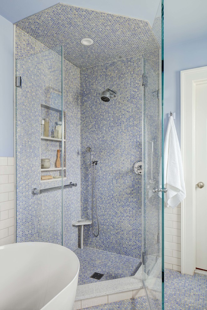This is an example of a mid-sized transitional master bathroom in New York with shaker cabinets, white cabinets, a freestanding tub, a corner shower, a two-piece toilet, white tile, ceramic tile, blue walls, porcelain floors, an undermount sink, engineered quartz benchtops, blue floor, a hinged shower door and white benchtops.