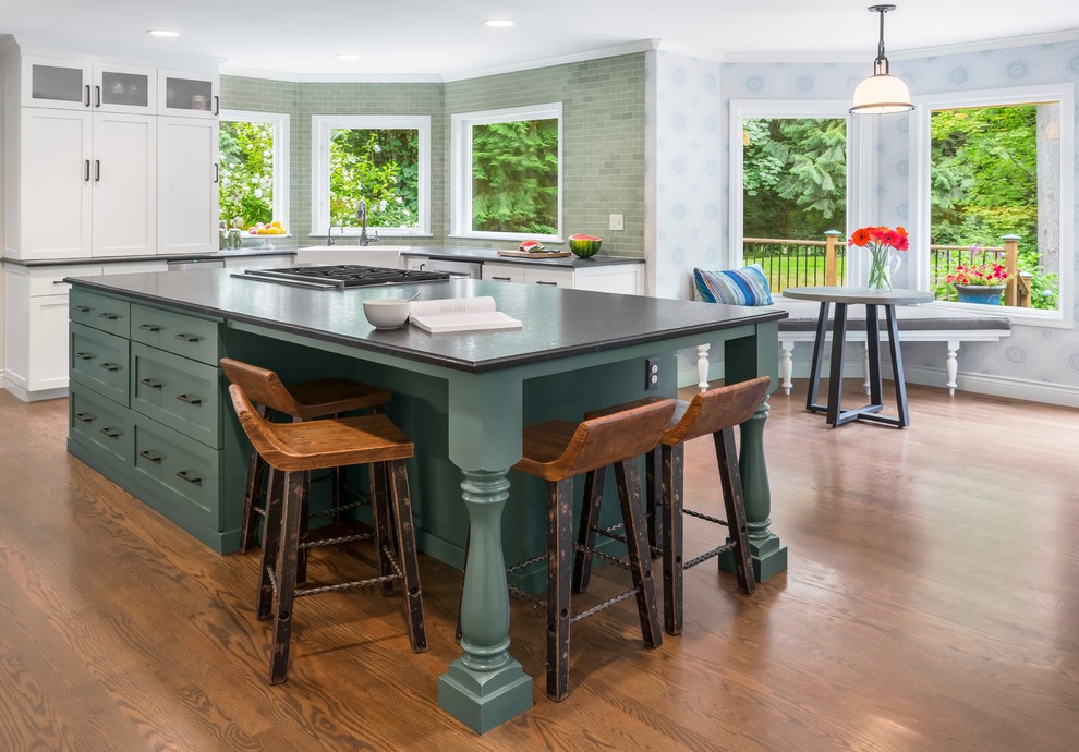 Inspiration for a mid-sized country u-shaped open plan kitchen in Seattle with a farmhouse sink, shaker cabinets, green cabinets, soapstone benchtops, green splashback, ceramic splashback, stainless steel appliances, medium hardwood floors, with island and brown floor.