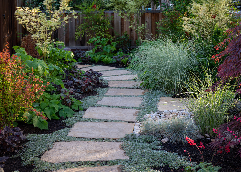 This is an example of a medium sized mediterranean side partial sun garden in San Francisco with a garden path, natural stone paving and a wood fence.
