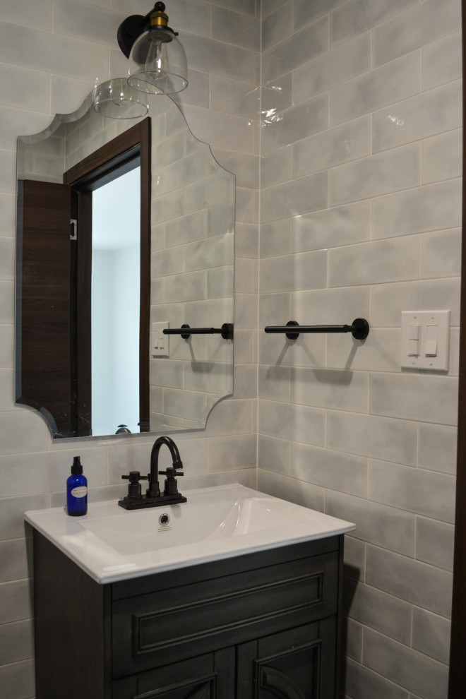 Пример оригинального дизайна: туалет среднего размера в стиле фьюжн с фасадами с утопленной филенкой, серыми фасадами, унитазом-моноблоком, серой плиткой, плиткой кабанчик, серыми стенами, полом из керамической плитки, монолитной раковиной, серым полом, белой столешницей и напольной тумбой