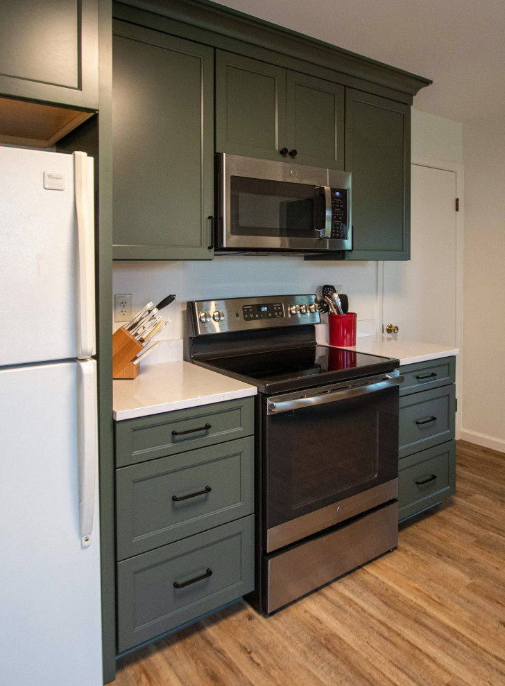 Design ideas for a mid-sized transitional galley eat-in kitchen in Cleveland with an undermount sink, recessed-panel cabinets, green cabinets, quartz benchtops, black appliances, light hardwood floors, no island, brown floor and beige benchtop.