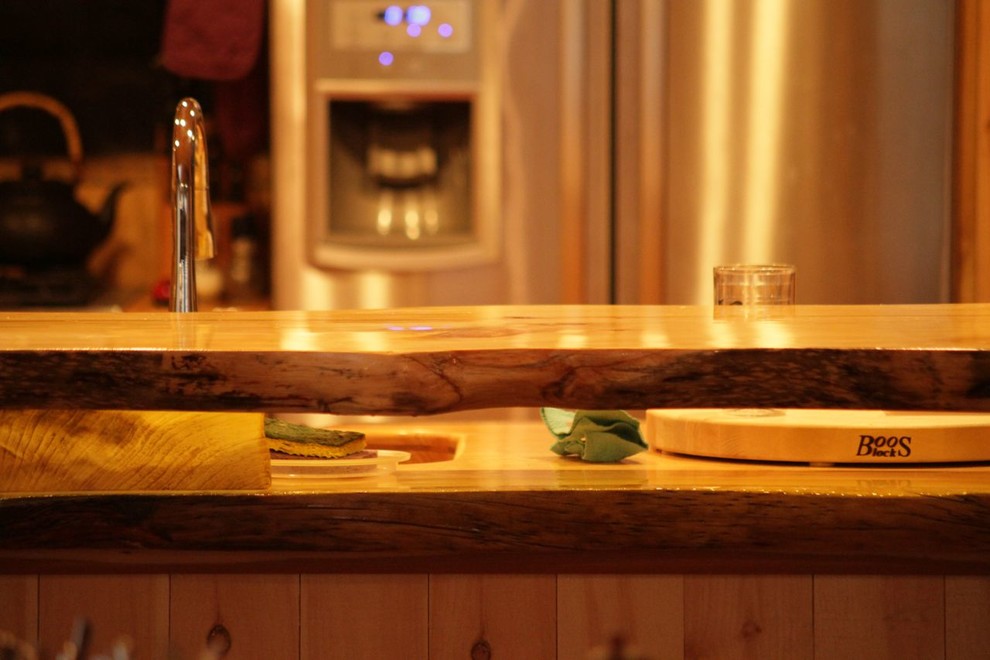 Example of a mid-sized mountain style u-shaped medium tone wood floor eat-in kitchen design in Burlington with an undermount sink, flat-panel cabinets, light wood cabinets, wood countertops, metallic backsplash, metal backsplash, stainless steel appliances and a peninsula