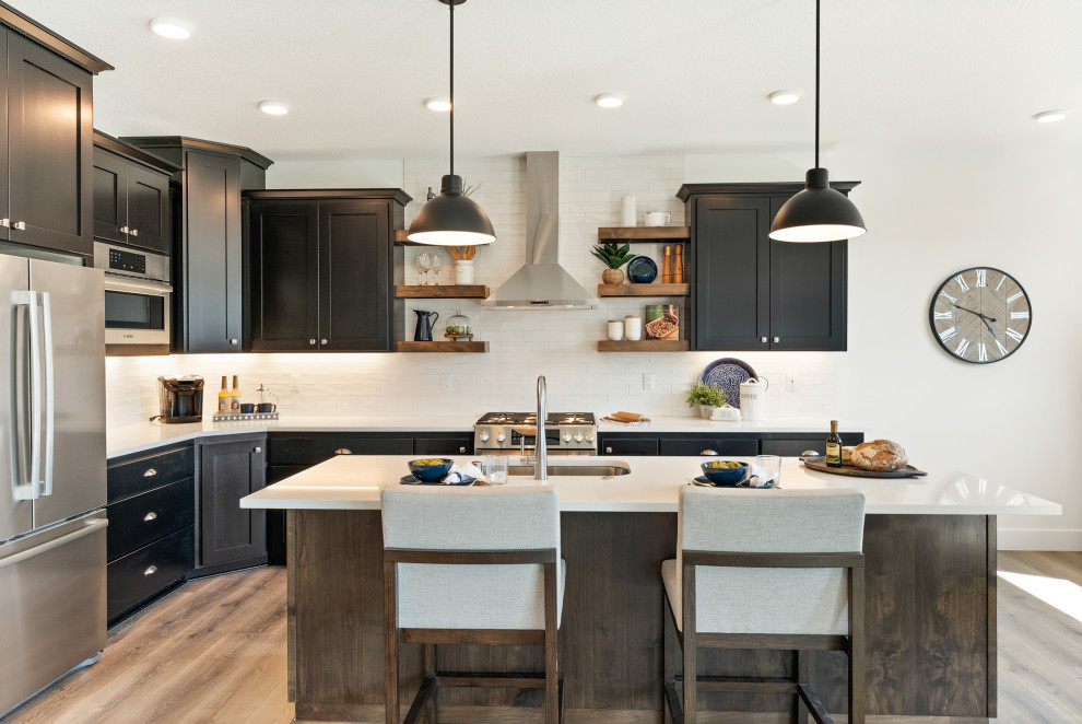 This is an example of a mid-sized contemporary u-shaped open plan kitchen in Portland with raised-panel cabinets, dark wood cabinets, quartzite benchtops, white splashback, subway tile splashback, with island and white benchtop.
