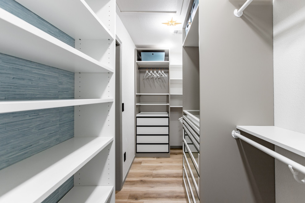 This is an example of a large modern storage and wardrobe in Las Vegas with glass-front cabinets, white cabinets, vinyl floors and beige floor.