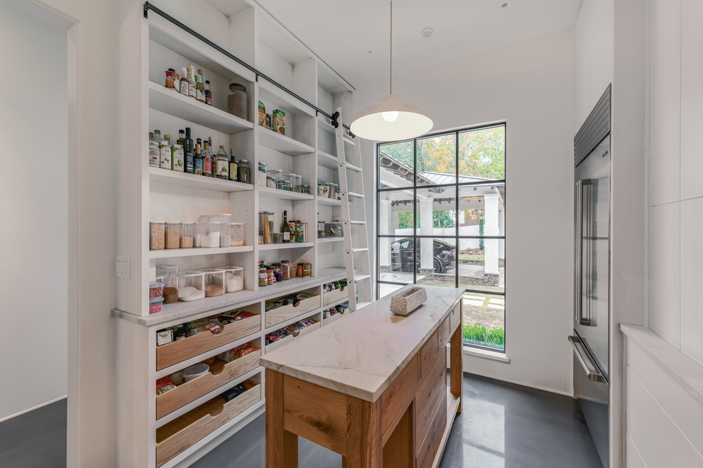 Kitchen pantry - concrete floor and gray floor kitchen pantry idea with an undermount sink, flat-panel cabinets, white cabinets, marble countertops, gray backsplash, marble backsplash, stainless steel appliances, an island and gray countertops