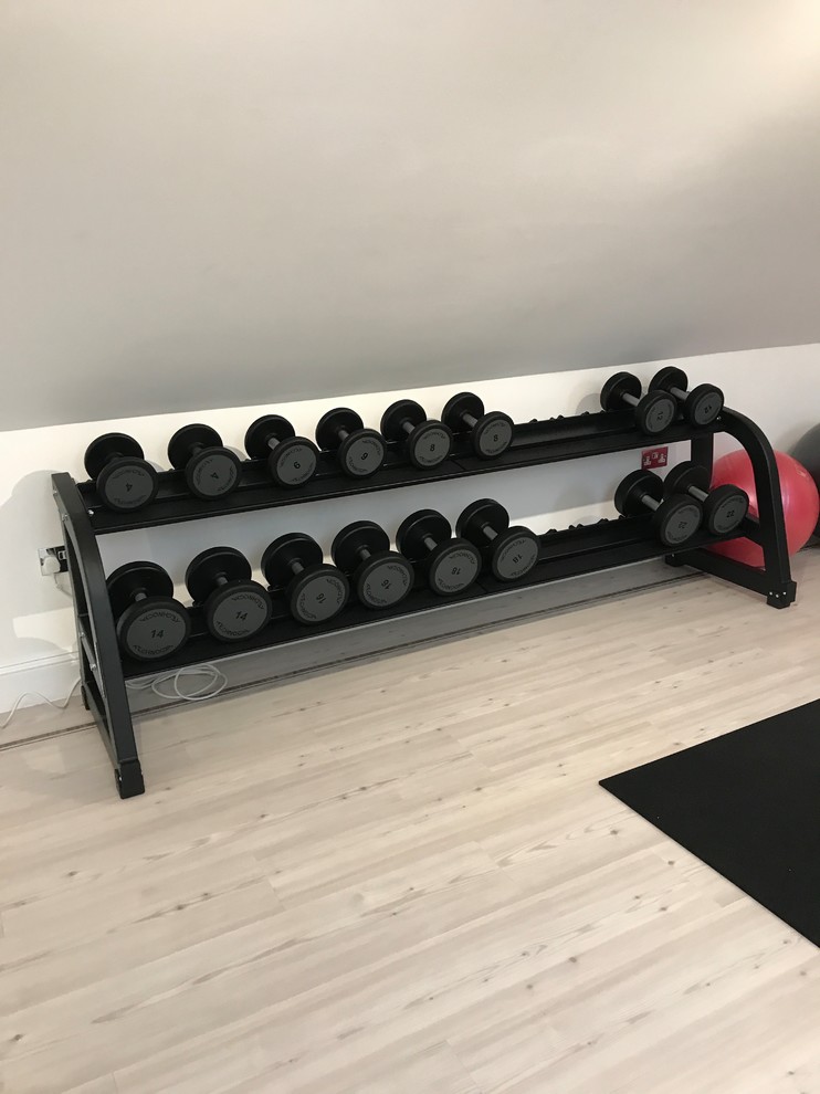 This is an example of a small contemporary home weight room in London with beige walls, light hardwood floors and white floor.