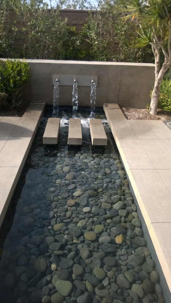 Photo of a mid-sized contemporary backyard full sun garden in Salt Lake City with a water feature, concrete pavers and a stone fence.