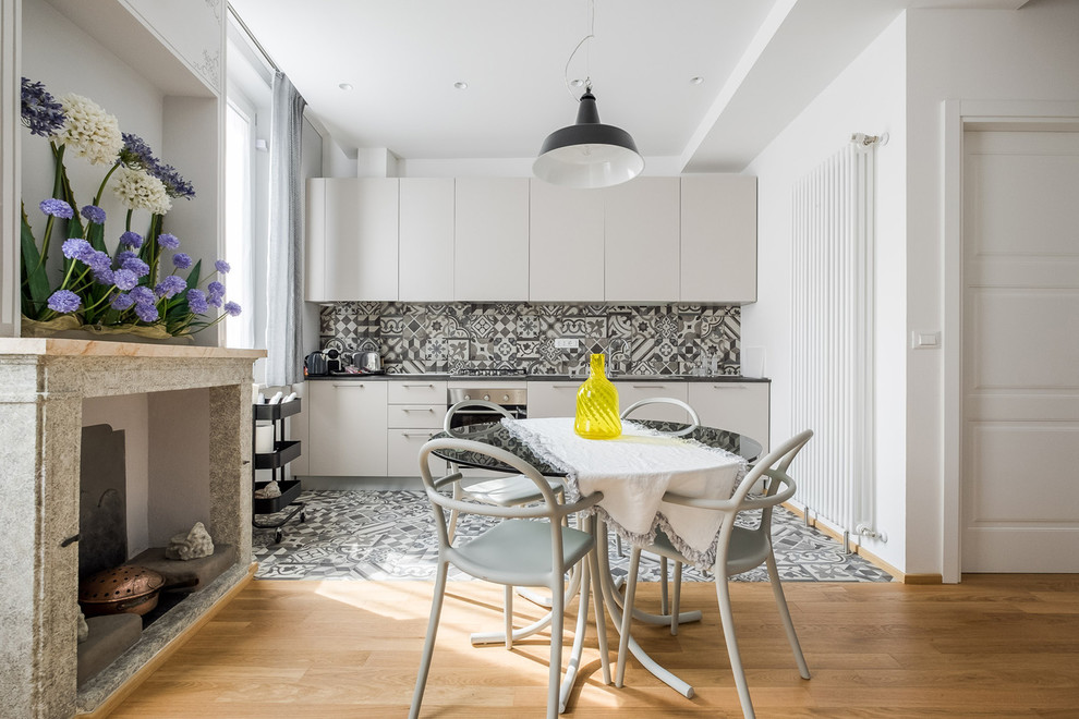 Photo of a modern single-wall eat-in kitchen in Bologna with flat-panel cabinets, white cabinets, grey splashback, cement tile splashback, cement tiles, grey floor and grey benchtop.