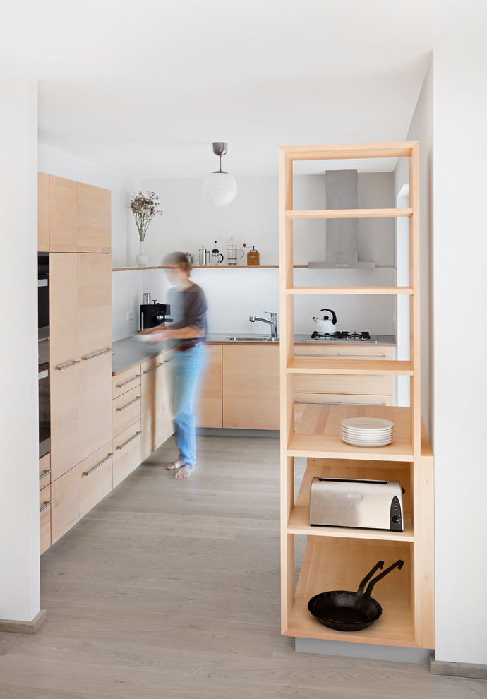 Photo of a mid-sized contemporary l-shaped separate kitchen in Stuttgart with flat-panel cabinets, light wood cabinets, laminate benchtops, grey splashback, timber splashback and grey benchtop.