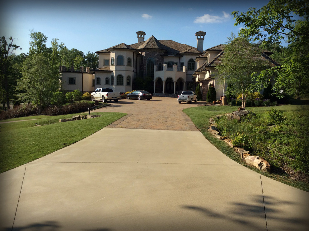 This is an example of a mid-sized traditional front yard full sun driveway in Other with brick pavers.