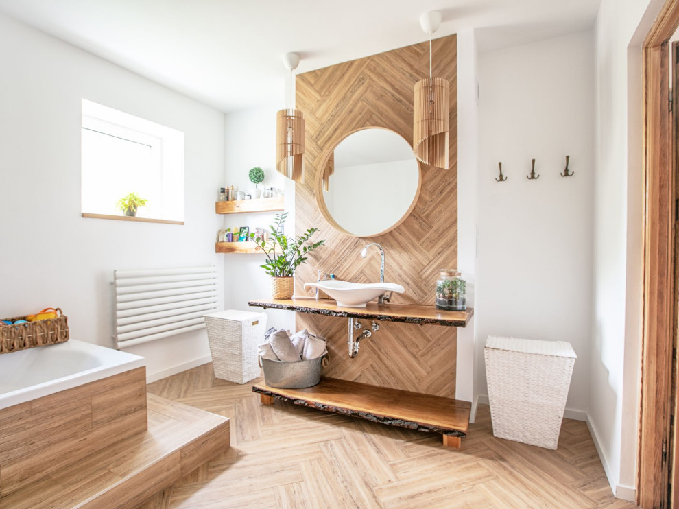 Photo of a large scandinavian ensuite bathroom in London with light wood cabinets, a built-in bath, white walls, medium hardwood flooring, a console sink, wooden worktops, brown floors, an open shower, a feature wall, a single sink and a floating vanity unit.