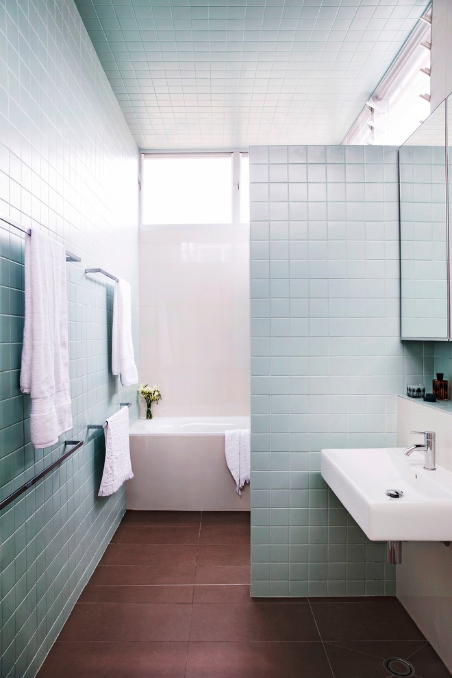 Photo of a mid-sized contemporary master bathroom in Sydney with a wall-mount sink, flat-panel cabinets, a drop-in tub, an alcove shower, a one-piece toilet, blue tile, ceramic tile, blue walls and porcelain floors.