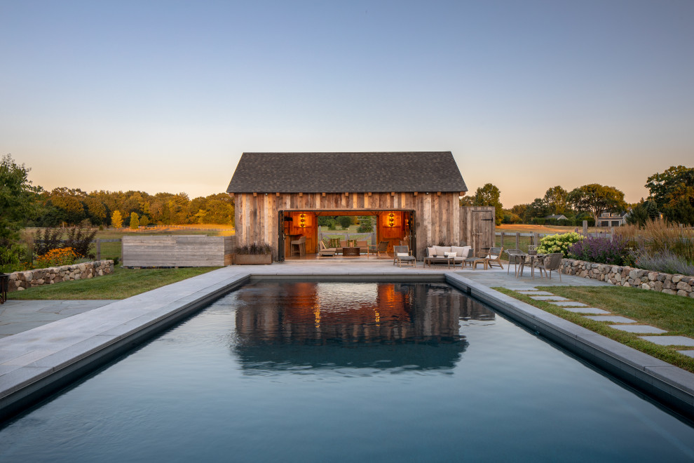 Идея дизайна: большой прямоугольный бассейн на заднем дворе в стиле кантри с домиком у бассейна и покрытием из каменной брусчатки