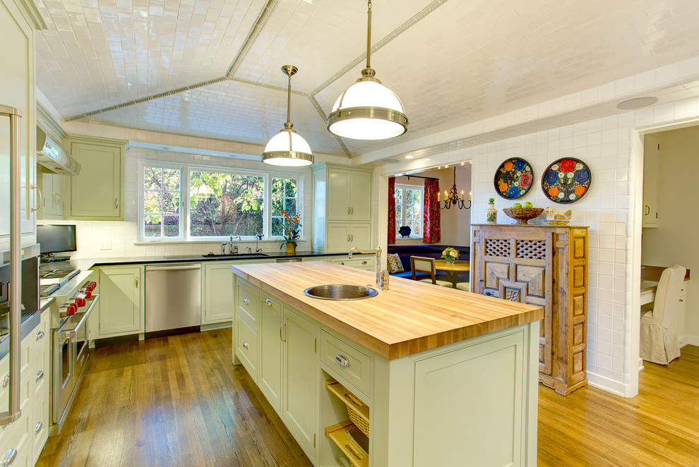 Mid-sized traditional l-shaped separate kitchen in Los Angeles with an undermount sink, recessed-panel cabinets, green cabinets, granite benchtops, white splashback, ceramic splashback, stainless steel appliances, medium hardwood floors and with island.