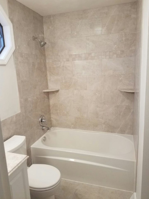 Alcove bathtub - mid-sized transitional white tile and porcelain tile porcelain tile and beige floor alcove bathtub idea with raised-panel cabinets, white cabinets, a two-piece toilet, beige walls, an undermount sink, marble countertops and white countertops