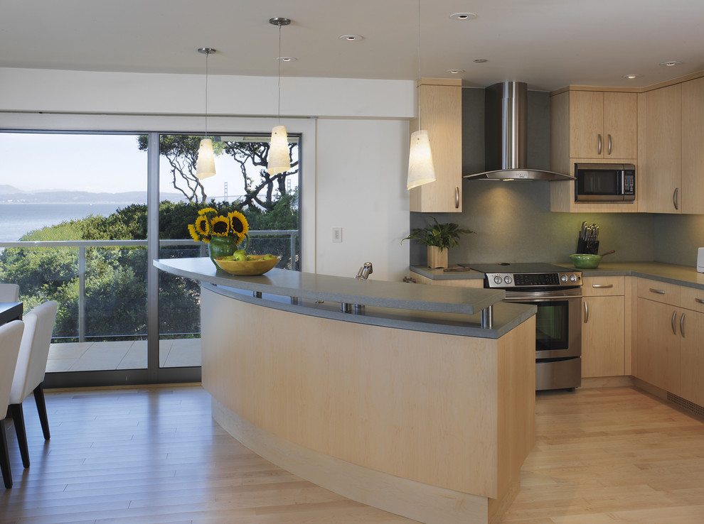 Design ideas for a mid-sized contemporary u-shaped eat-in kitchen in San Francisco with stainless steel appliances, flat-panel cabinets, light wood cabinets, quartz benchtops, an undermount sink, green splashback, light hardwood floors, with island and stone slab splashback.