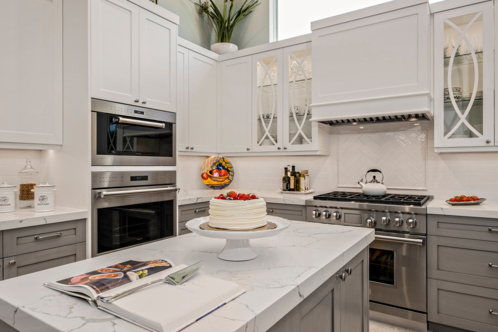 This is an example of a transitional kitchen in Other with a drop-in sink, white splashback, cement tile splashback, stainless steel appliances, marble floors and white benchtop.