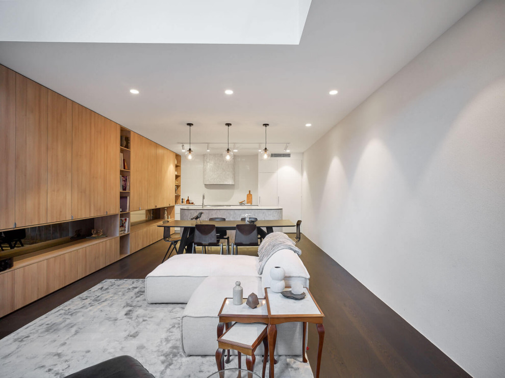 Mid-sized modern open concept living room in Melbourne with yellow walls, dark hardwood floors, a concrete fireplace surround, a concealed tv and brown floor.