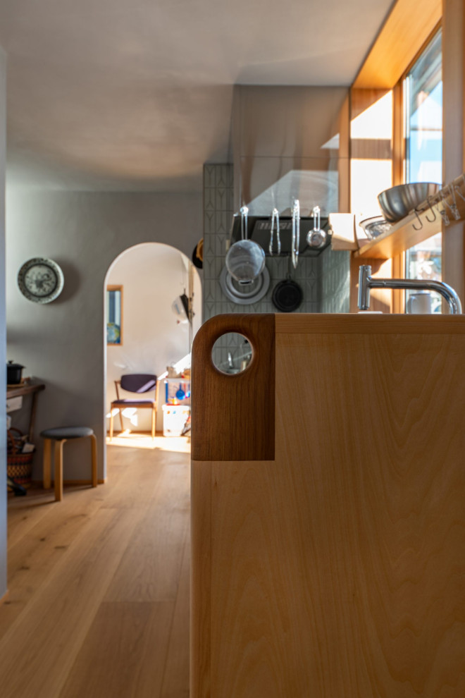 Exempel på ett avskilt, litet nordiskt brun linjärt brunt kök, med en integrerad diskho, luckor med infälld panel, skåp i mellenmörkt trä, bänkskiva i rostfritt stål, grått stänkskydd, stänkskydd i keramik, rostfria vitvaror, plywoodgolv och brunt golv