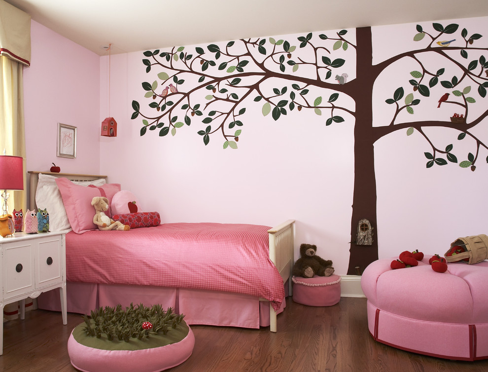 This is an example of a transitional kids' bedroom for kids 4-10 years old and girls in Chicago with pink walls and medium hardwood floors.
